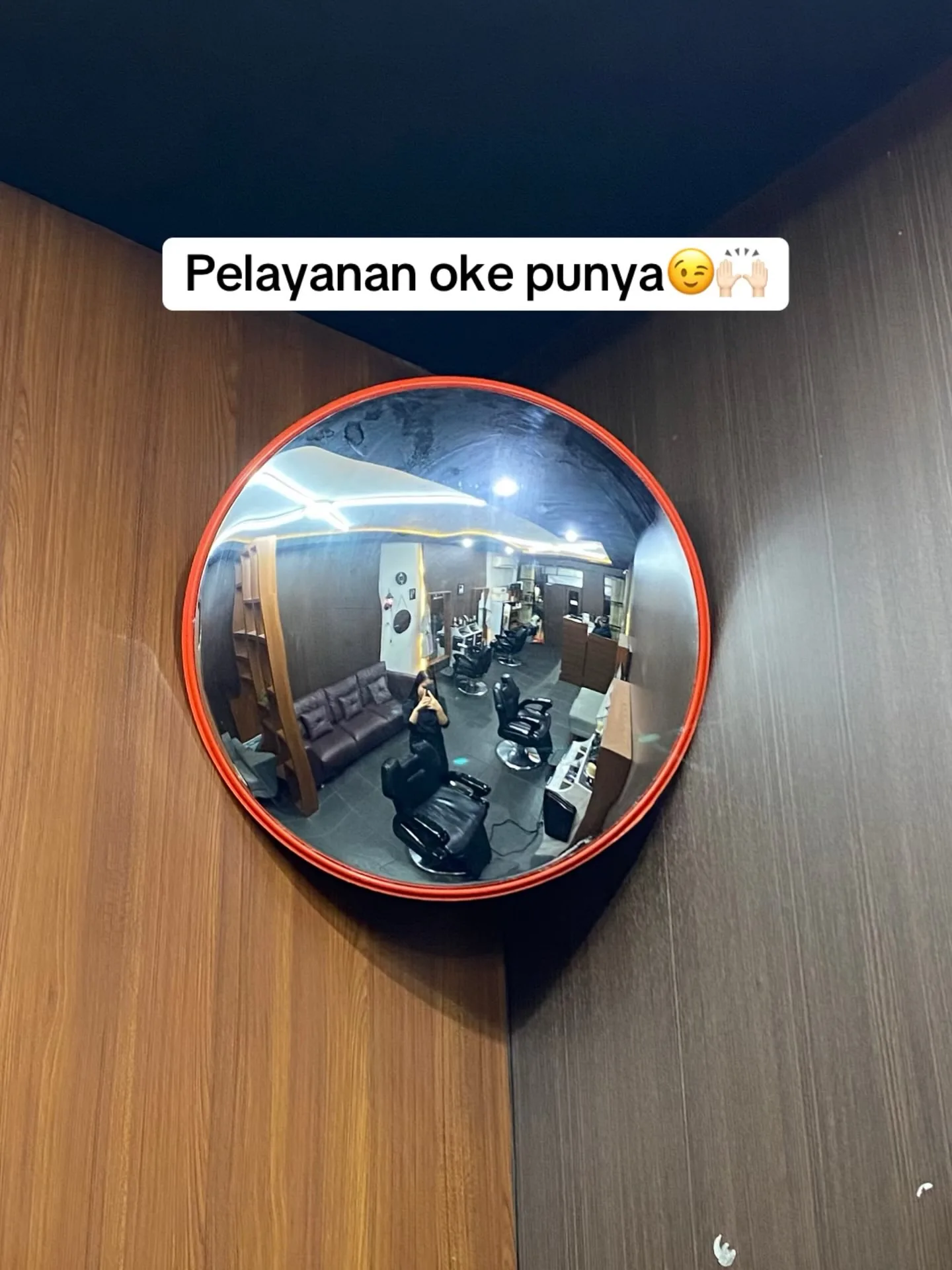 Cermin cembung memantulkan ruang cukur dan sofa tunggu Ken'z Barbershop Malang